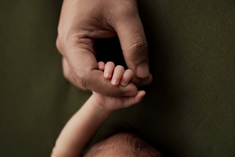 Newborns fingers dads hand